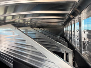 Interior view of an empty Elite 6 metal livestock trailer, showing angled support beams and vented side panels with windows allowing light to enter&mdash;model #23223 from Horse Smart Tack. -Stillwater Trailer Sales