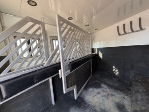 A horse stable with a metal railing sits beside new and used Stock Trailers, offering convenient access for your horses. -Stillwater Trailer Sales