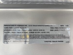 A close-up of a vehicle information label for an Elite 30' Cattle Combo trailer, showing specifications such as GVWR, GAWR, tire size, and cold tire pressure from Elite Trailer Manufacturing L.L.C. -Stillwater Trailer Sales