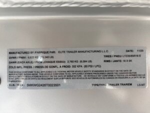 A manufacturer label on an Elite Trailers stock trailer displays vital information—GVWR, GAWR, tire size, rim size, cold tire pressure, VIN, and type—all in both English and French. -Stillwater Trailer Sales
