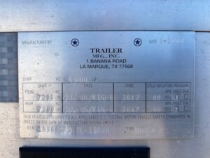 A metal manufacturer&rsquo;s label for a 2001 Bloomer 3 Horse trailer displays specifications including model, location, weight ratings, tire size, date, and VIN number. Text is engraved and some information is handwritten. -Stillwater Trailer Sales