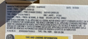 Close-up of a vehicle information label on a Swift Built 28' stock trailer, showing manufacturer (Rawmaxx), date (01/2026), weight limits, tire specs, VIN, and tire pressure in English and French. -Stillwater Trailer Sales