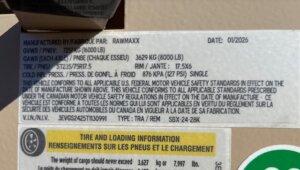 A close-up of a vehicle information sticker showing manufacturing details, tire and loading information, specifications like GVWR, GAWR, VIN number, and safety compliance notices in English and French. -Stillwater Trailer Sales