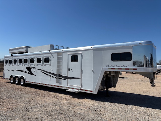 A large silver gooseneck horse trailer with ten windows, three axles, and black decorative graphics is parked on gravel under a clear blue sky. -Stillwater Trailer Sales