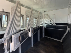 Interior of a 5 horse side load Bloomer horse trailer, featuring Outlaw interior touches, metal dividers, padded partitions, and windows along the side for safe and comfortable transport of multiple horses. -Stillwater Trailer Sales