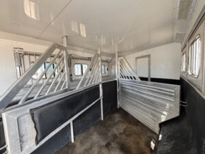 Interior of a Cimarron 4 Horse trailer with metal dividers, rubber padding, non-slip floor, and windows on the right side. Designed for safe transport of multiple horses, this model also features convenient side load access. -Stillwater Trailer Sales