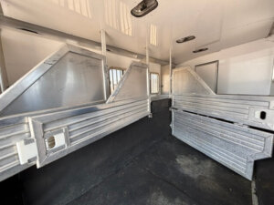 The interior of this Featherlite 4 Horse trailer features metal dividers, rubber flooring, and barred windows, designed to safely transport multiple horses in separate stalls. -Stillwater Trailer Sales