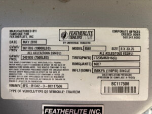 Close-up of a Featherlite manufacturer&rsquo;s data label for a 4 Horse trailer, showing details such as date (May 2010), GVWR, model number, tire and rim size, VIN, and load capacities in both English and French. -Stillwater Trailer Sales